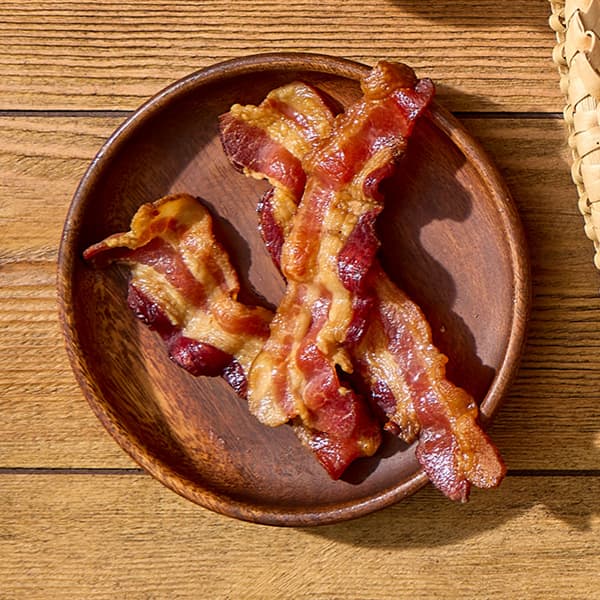 A small plate with crispy bacon sits atop a picnic table.