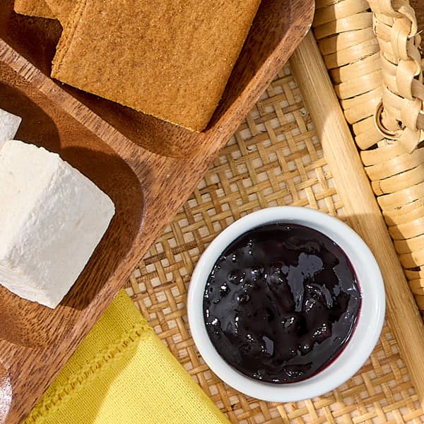 A small container of jam placed alongside Vosges Naked Vanilla Marshmallows and grahams from the Campfire S'mores Kit.