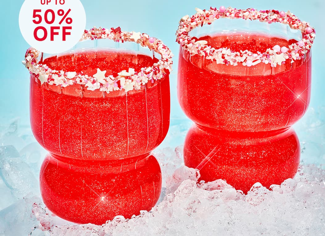 Two glasses filled with a bright red glittery drink sit on a bed of crushed ice