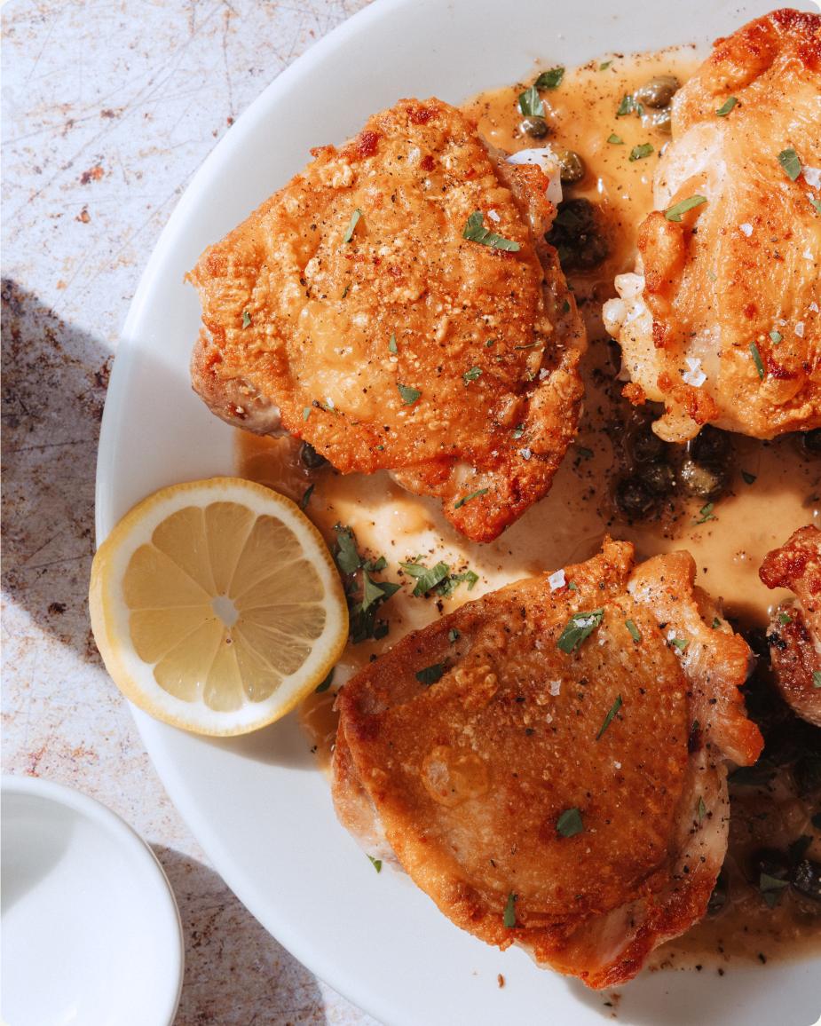 Crispy pan-seared chicken thighs with shallot pan sauce on a plate