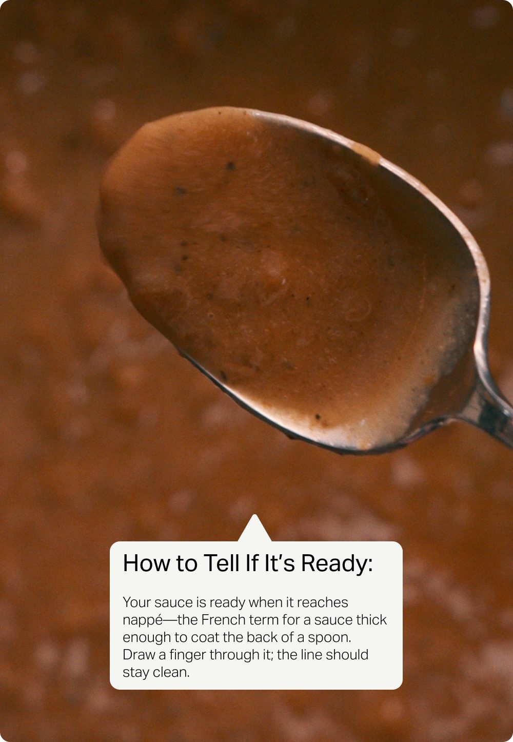 A spoon coated with glossy pan sauce, with a note explaining how to tell when the sauce is ready