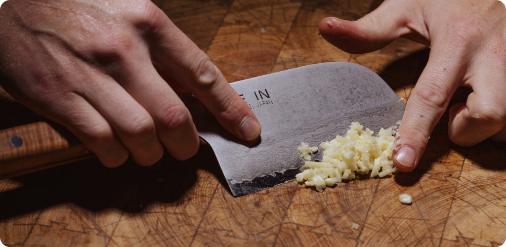 Chopping garlic with the Kamagata knife on a wooden board