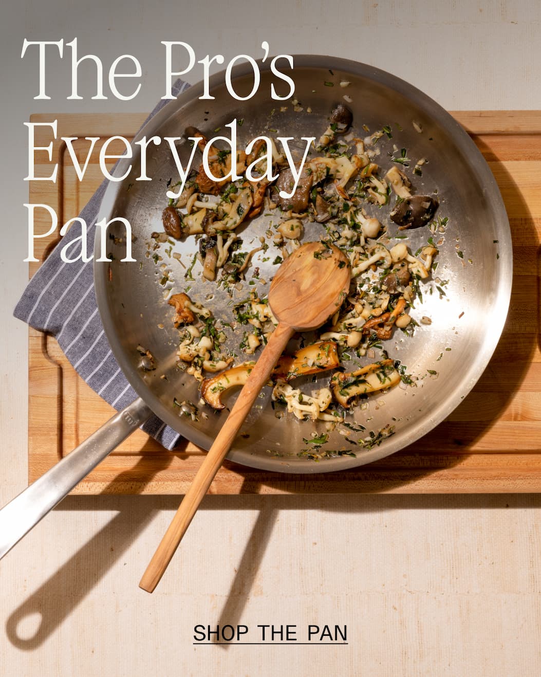 Stainless Clad Pan with sautéed mushrooms and herbs over a wooden board