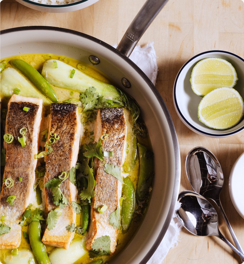 Weeknight salmon with Thai green curry cooking in a Sand CeramiClad pan, garnished with cilantro and served with lime and rice