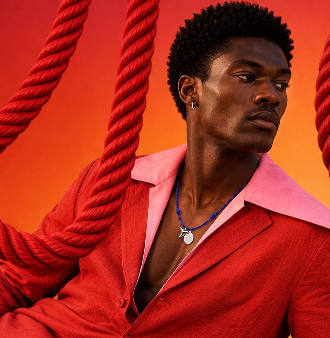 Man in red suit wearing rope necklace.