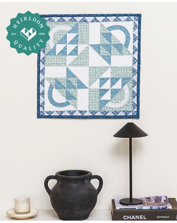 A handmade blue and green quilt hanging on a wall