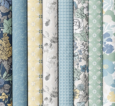 Folded fabrics in blues, creams, and greens with various floral patterns. >>