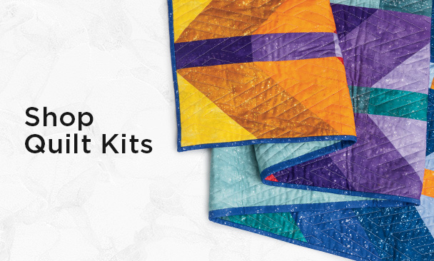 Text: Shop Quilt Kits Image: a colorful multi tonal quilt with modern chevron pattern and 