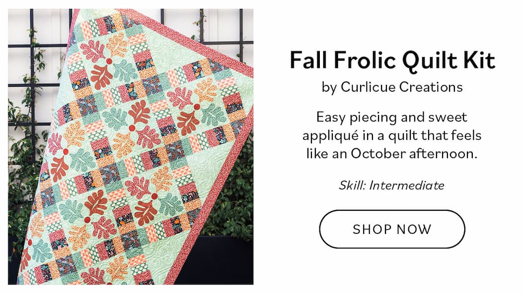 Image: A large quilt in autumn colors with fall leaf motif. Text: Fall Frolic Quilt Kit by Curlicue Creations  Intermediate Easy piecing and sweet appliqué in a quilt that feels like an October afternoon. Shop Now >>