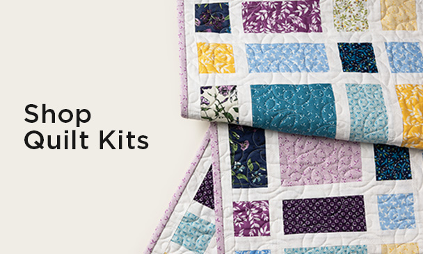 Text: Shop Quilt Kits Image: a colorful multi tonal quilt with modern chevron pattern