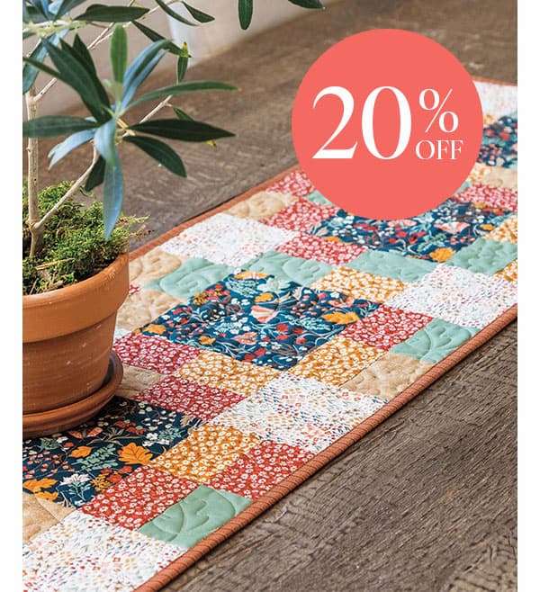Image: A quilted patchwork table runner. Text: 20% Off >>