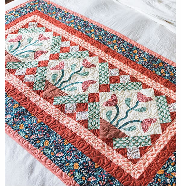 A handmade colorful quilt laying on a bed