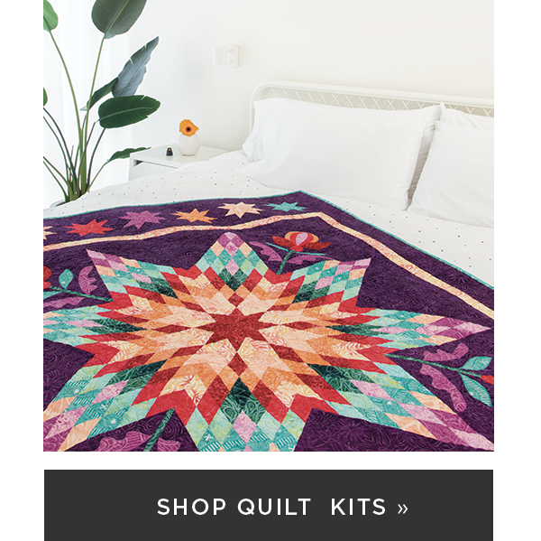 Image: A purple quilt with a large star motif flanked by flowers. Text: Shop Quilt Kits >>