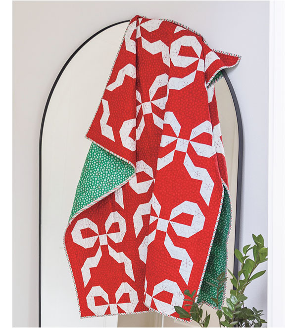 A red and white Christmas themed quilt draped over a mirror