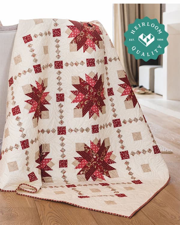 A white quilt with red accents draped over a chair