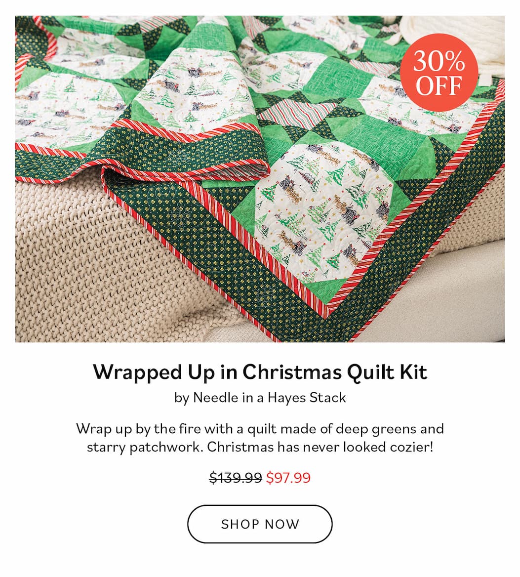 Image: A Christmas themed quilt in greens with red and white striped binding. Text: Wrapped Up in Christmas Quilt Kit by Needle in a Hayes Stack. Wrap up by the fire with a quilt made of deep greens and starry patchwork. Christmas has never looked cozier! Was $139.99, now $97.99. Shop Now >>