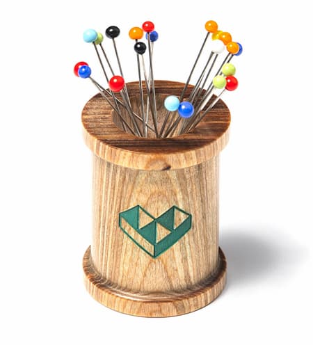 A wood magnetic spool filled with quilting pins