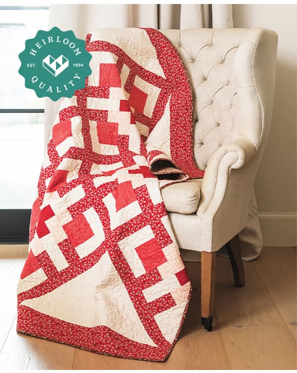 A handmade red and white quilt draped over a chair