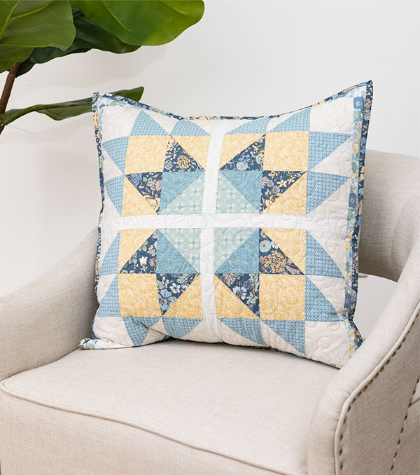 A handmade quilted pillow sitting on a white chair
