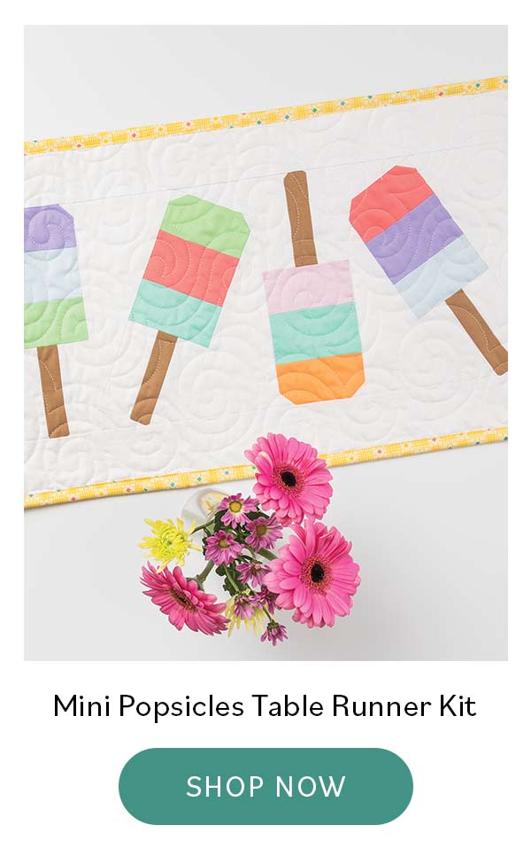 Image: A quilted table runner with white background and bright colorful popsicles. Text: Mini Popsicles Table Runner Kit. Shop Now >>