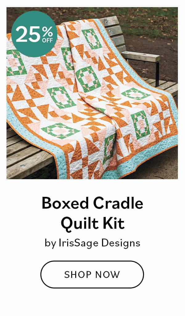 Image: A teal and orange quilt draped over a park bench. Text: Boxed Cradle Quilt Kit by IrisSage Designs. Shop Now >>