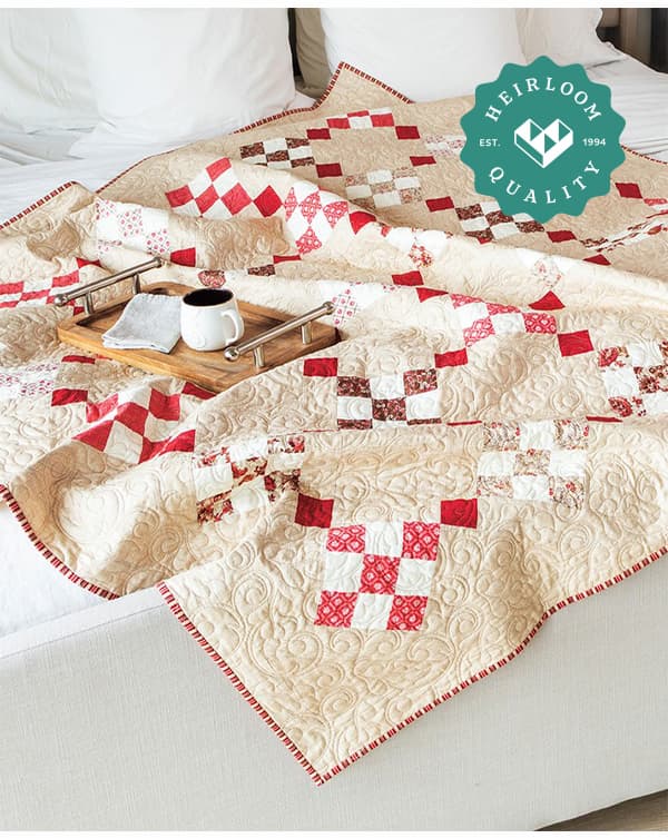 A handmade red and white quilt draped over a bed