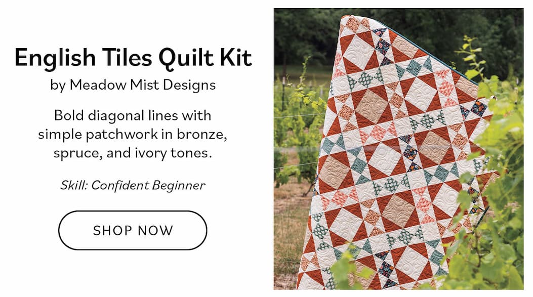 Image: A fall themed quilt with diagonal lines and patchwork. Text: English Tiles Quilt Kit by Meadow Mist Designs. Bold diagonal lines with simple patchwork in bronze, spruce, and ivory tones. Skill: Confident Beginner. Shop Now >>