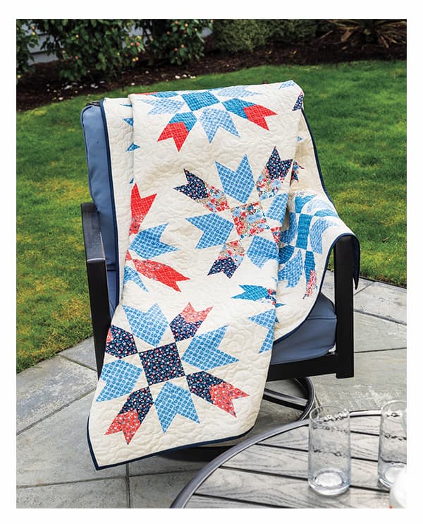A white quilt with red, white, and blue stars. >>