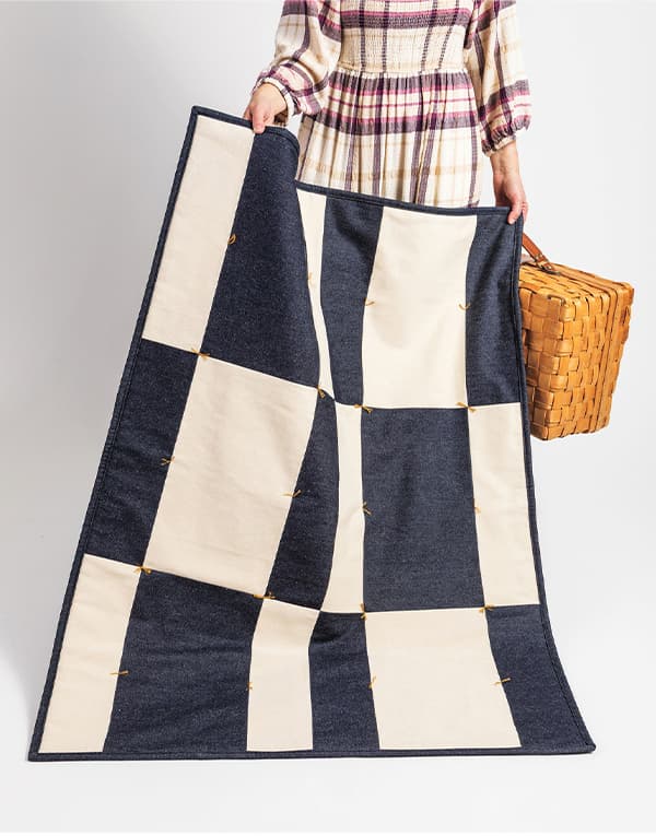  model holding a blue and cream colored thick handmade quilt