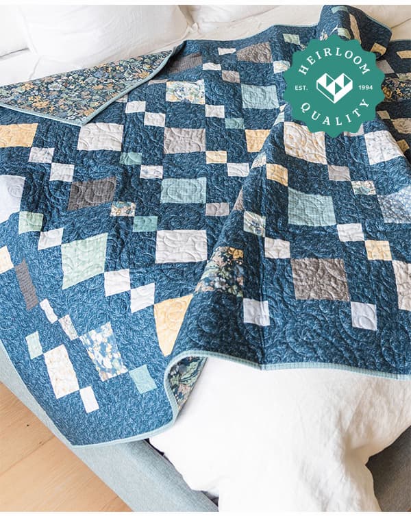A handmade blue and green quilt draped over a bed