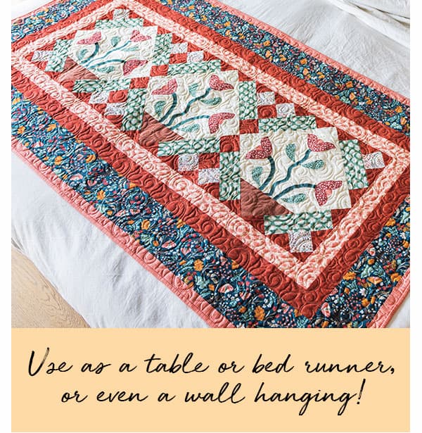 Image: A quilted runner with floral fabrics and blocks. Text: Use as a table or bed runner or even a wall hanging! >>
