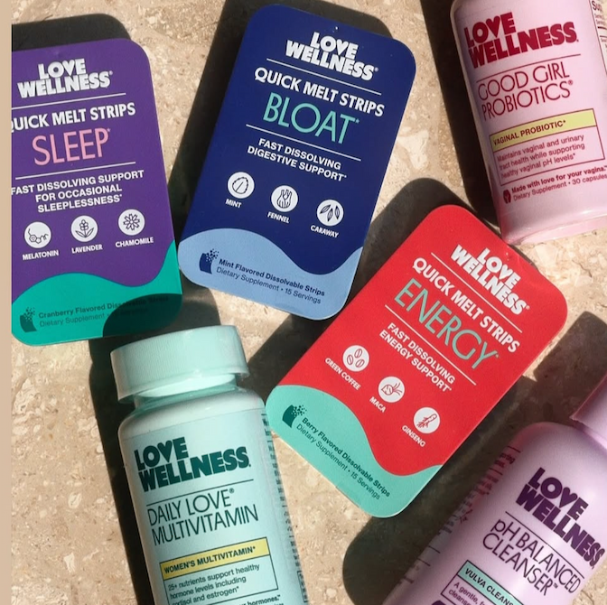 Flat lay of Love Wellness products on a marble surface, including Quick Melt Strips in Sleep, Bloat, and Energy flavors, Good Girl Probiotics, Daily Love Multivitamin, and pH Balanced Cleanser.