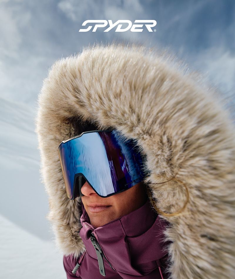 Close-up photo of skier wearing blue lens goggle and a hood with an oversized fur trim
