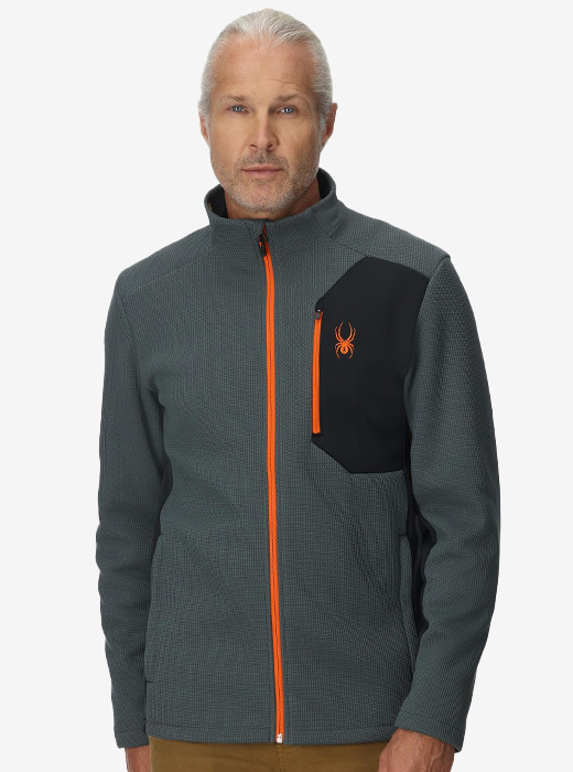 Man in a studio wearing Bandit Jacket in slate blue and orange colorway 