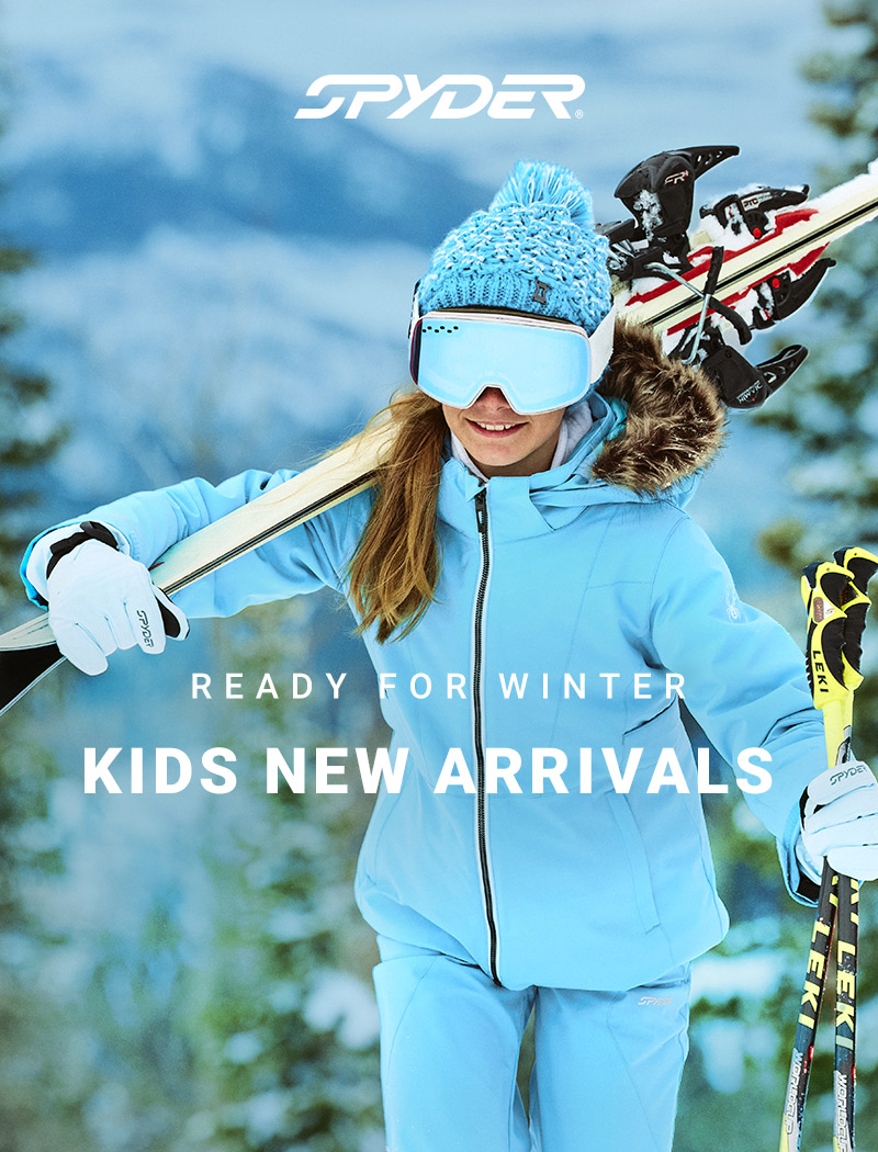 Girl skier walking up the hill in a bright blue forest wearing blue Spyder jacket and pants