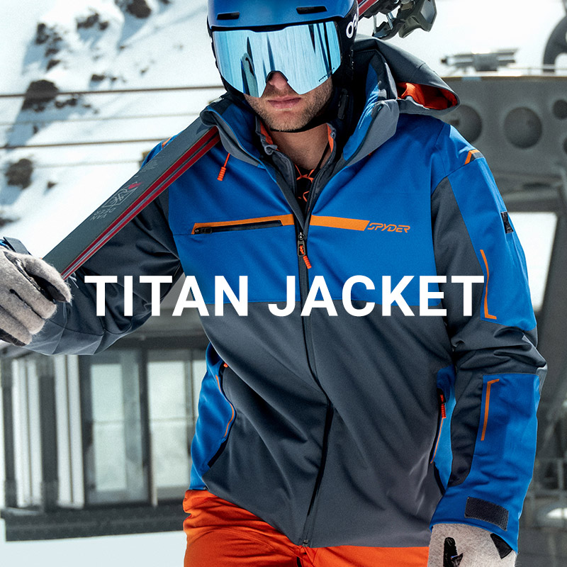 Skier walking up with skis in a blue jacket. Message: Titan Jacket