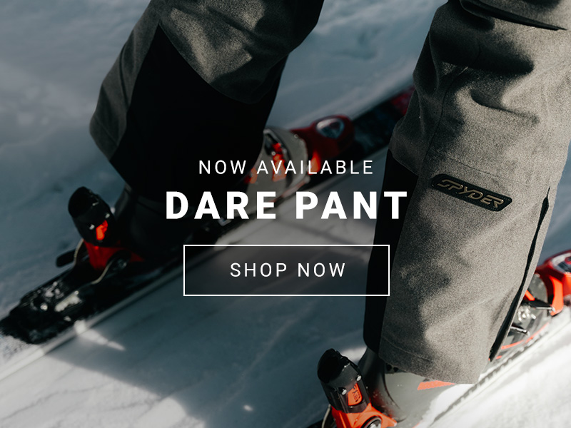 Tight shot of the bottom of ski pants and skis with a Spyder logo on the back leg.