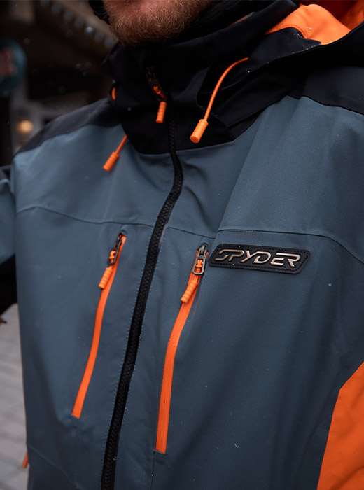Detail chest of the Vyper Jacket in Slate Blue with orange zipper and drawcord accents