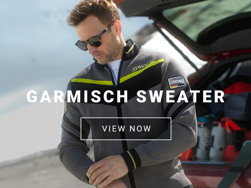 Male in a sporty ski sweater with a open car hatchback showing ski gear in the background.