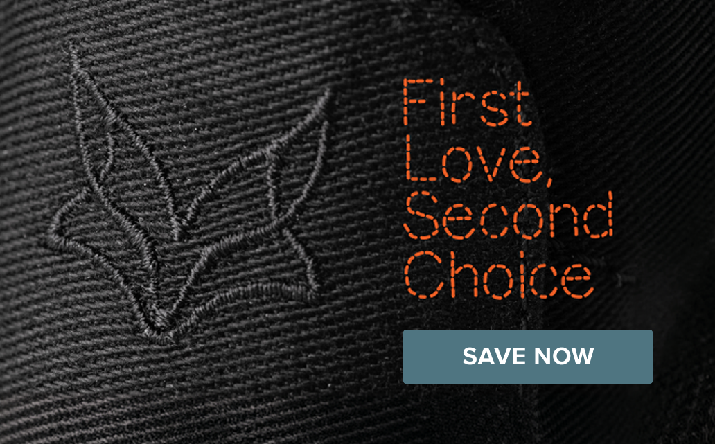 Close-up of a black fabric featuring an embroidered fox silhouette and the orange text "First Love, Second Choice" in a stitched font.