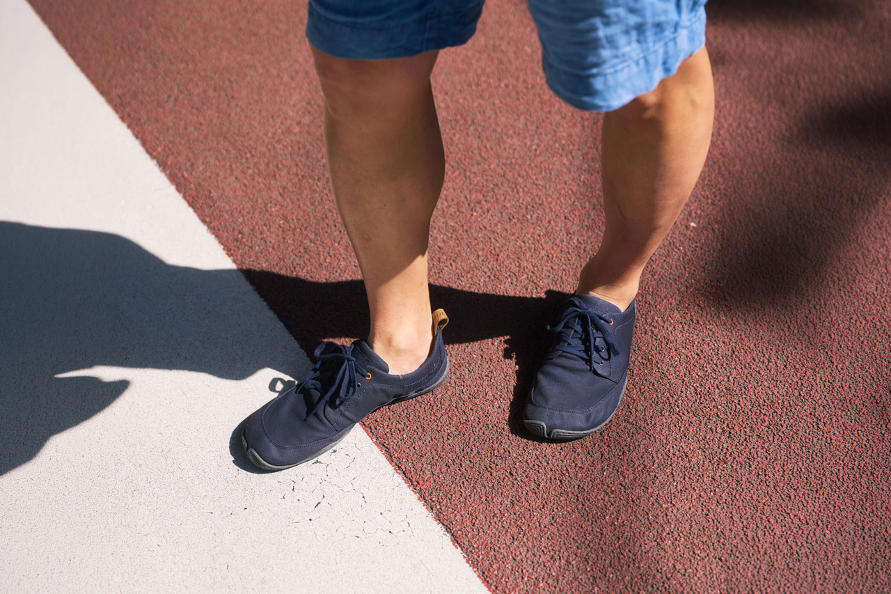 A man is standing on a tartan track; you can see his lower legs, and he is wearing Tanuki Umi