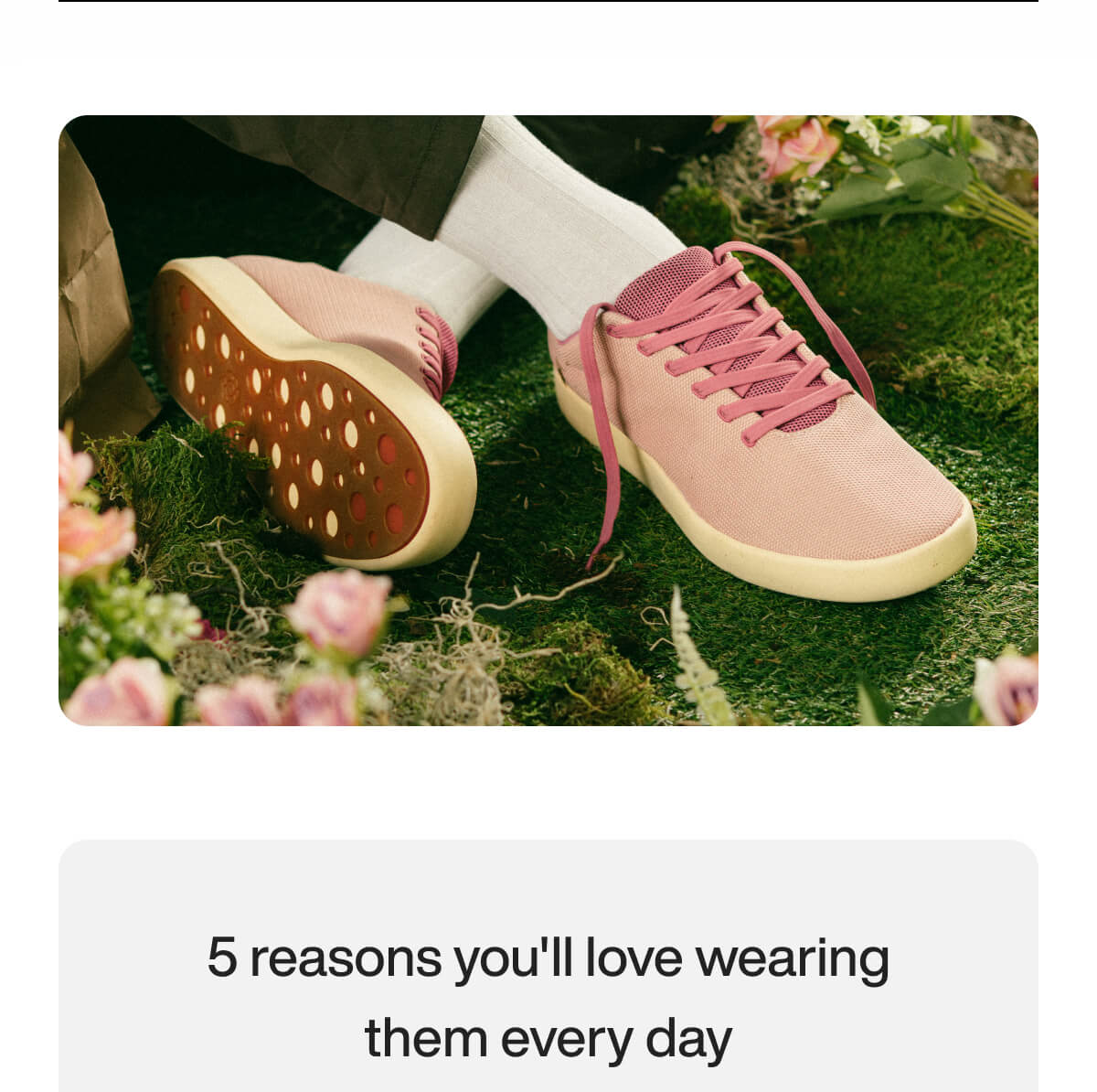 A person wearing pink sneakers with white socks stands on vibrant green moss, surrounded by pink flowers. The scene evokes a fresh, natural feel.