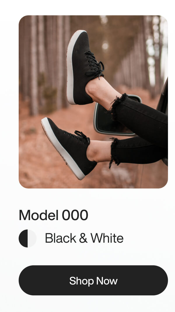 Person wearing black sneakers with white soles, feet propped outside a car window. Background features a serene forest. Text reads "Model 000, Black & White, Shop Now."