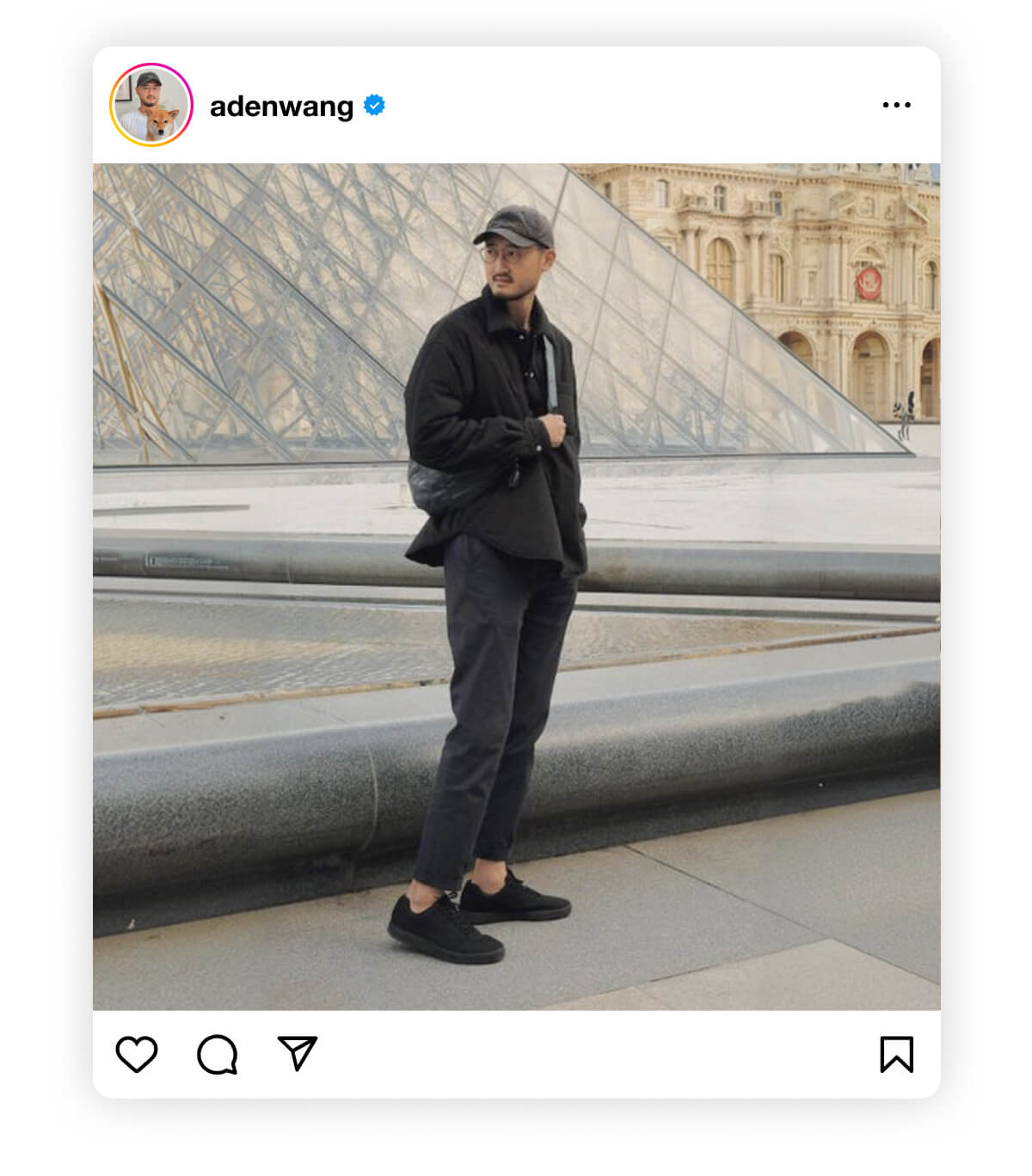 Man in a black outfit and cap standing outside the Louvre Pyramid in Paris. The setting is modern and iconic, evoking a sense of travel and style.