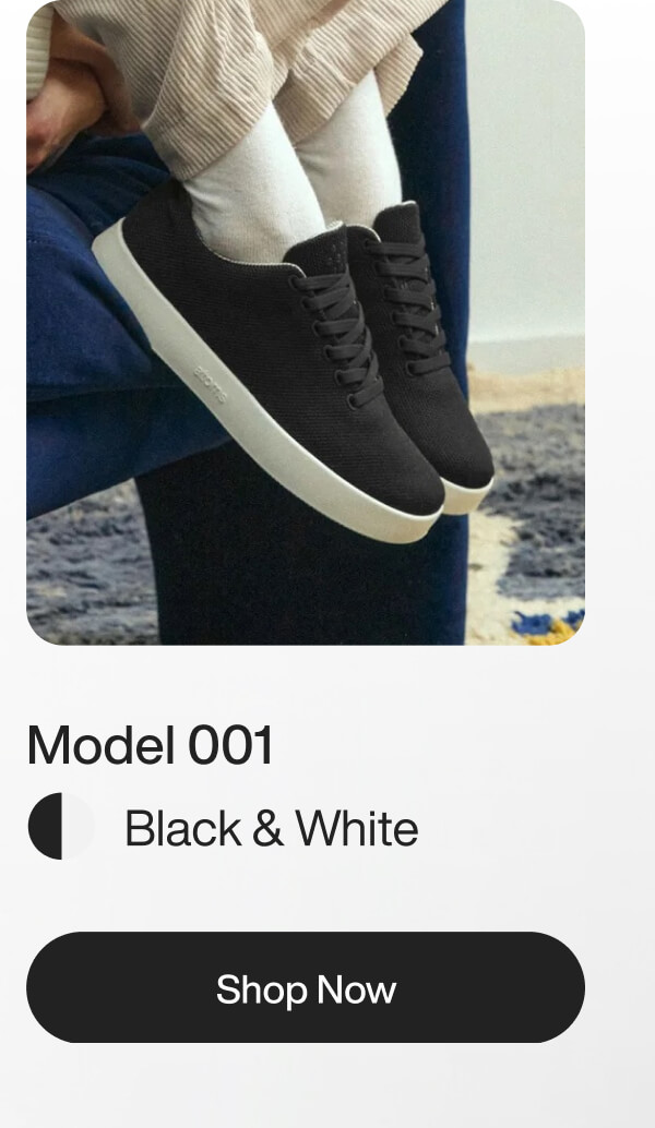 A person in a white sweater and light pants sits on a blue chair, wearing black sneakers. The setting is minimalistic with a modern, calm vibe. Text reads "Model 001 Black & White" with a "Shop Now" button.