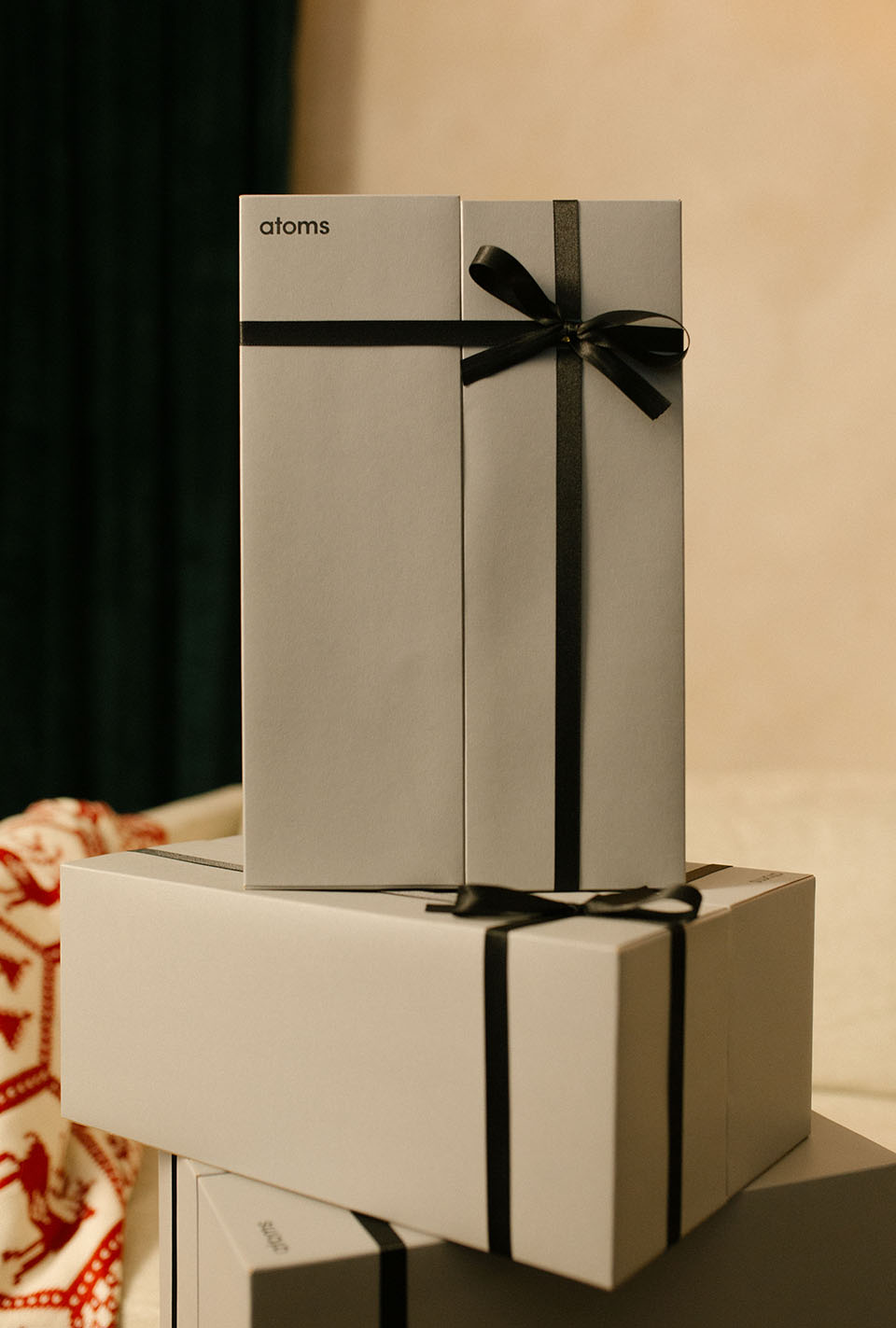 A stack of Atoms shoe boxes gift-wrapped with black ribbon bows.