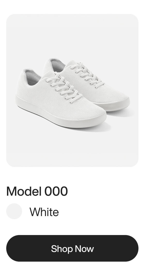 A pair of minimalist white sneakers with matching laces and textured fabric uppers on white.