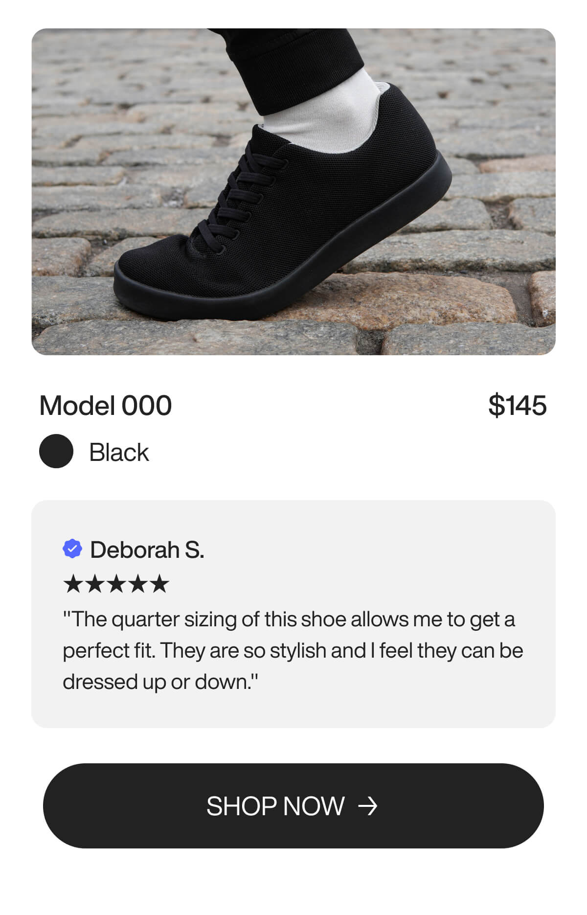 Black sneaker on cobblestone sidewalk, worn with white socks and black pants. Priced at $145, it receives a five-star review praising its stylish versatility.