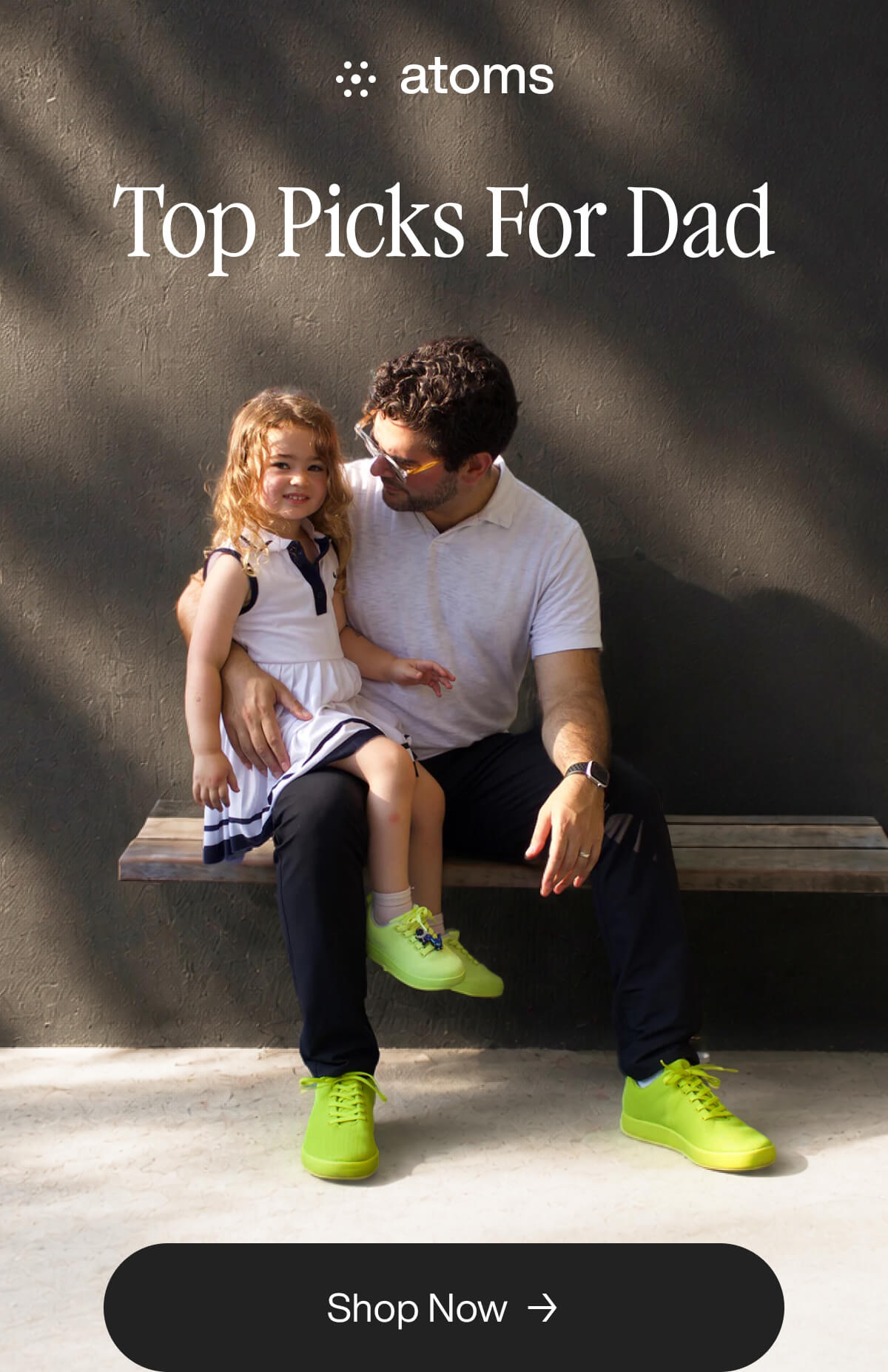 A man and a little girl sitting on a bench, the man is wearing yellow shoes and holding the little girl.