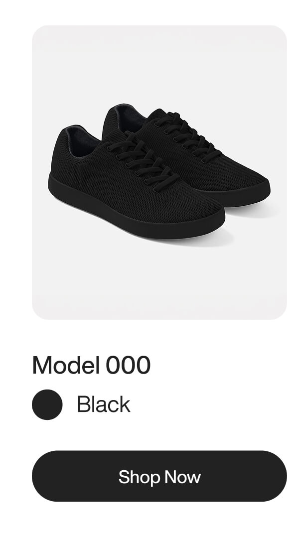 A pair of minimalist black sneakers with matching laces and soles on a white background.